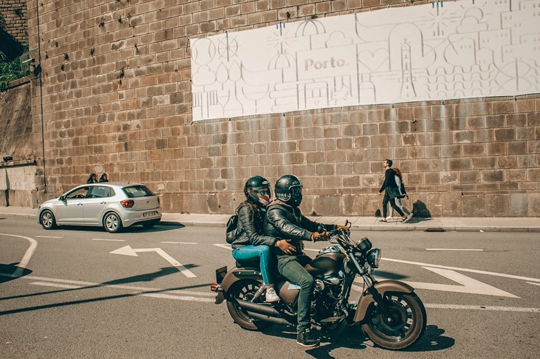 Homem e mulher passeiam de moto na cidade do Porto, em Portugal