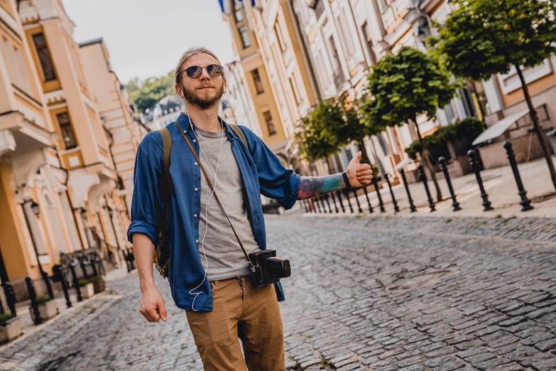 Um homem com uma câmara fotográfica numa rua de calçada.