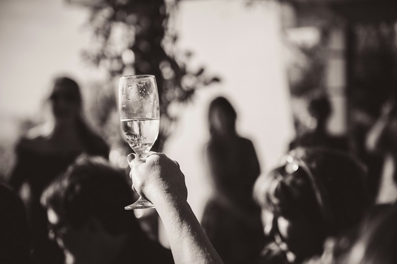 Uma pessoa segura graciosamente um copo de vinho durante um discurso de casamento