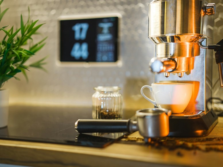 Máquina de café expresso a preparar café numa chávena branca numa bancada moderna da cozinha.