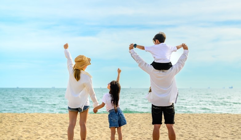 Família - pais e um pequeno casal - diverte-se durante as férias na praia e à beira-mar