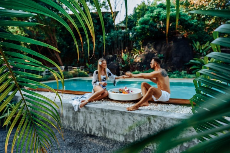 casal de férias, à beira da piscina, num hotel de luxo