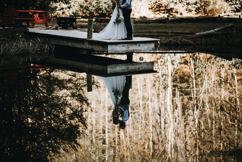 Reflexo de um casal de noivos junto a um lago