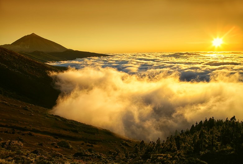 Monte Teide, em Tenerife, nas Ilhas Canárias. Pôr do sol dourado diante um mar de nuvens