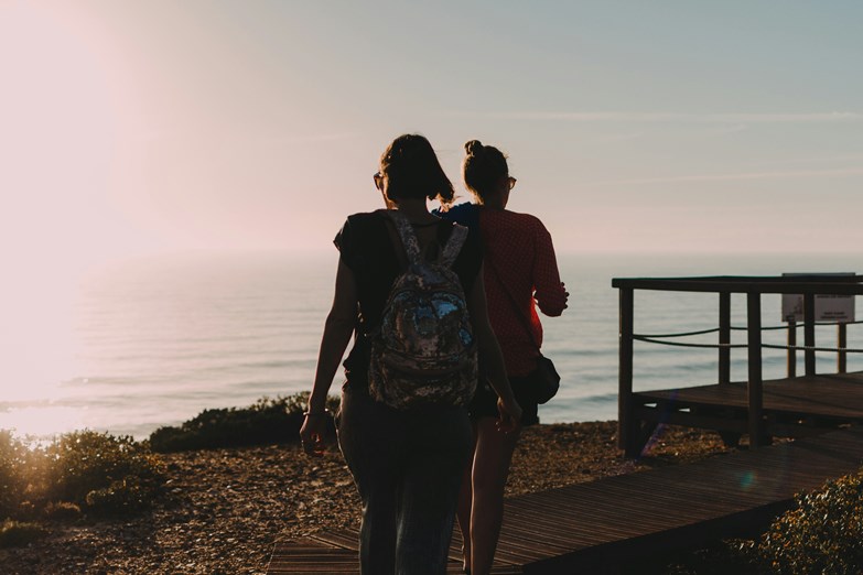 Duas mulheres a passear numa falésia da costa portuguesa durante o pôr do sol