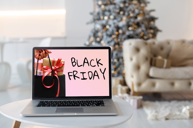 Ecrã de computador portátil mostra uma imagem da Black Friday, com uma árvore de Natal ao lado do sofá da sala de estar em segundo plano