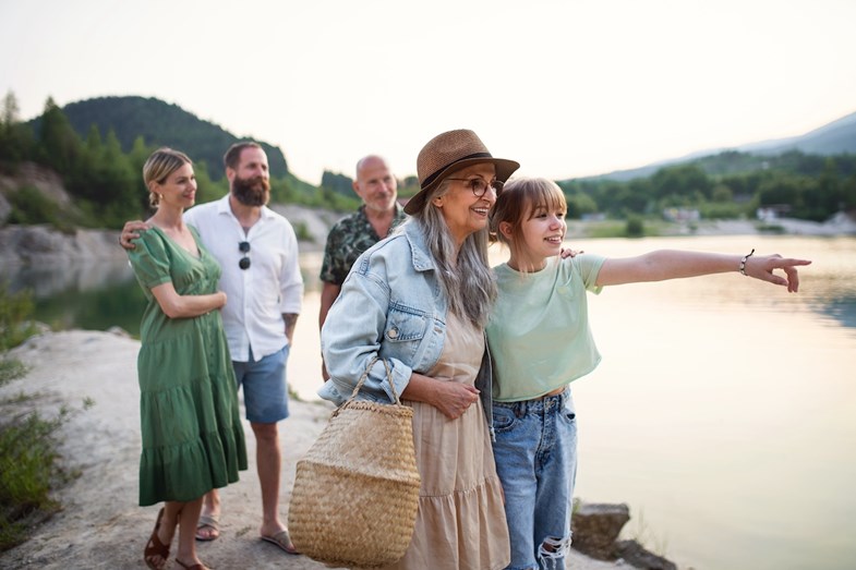 Família intergeracional passeia junto a um lago ao entardecer